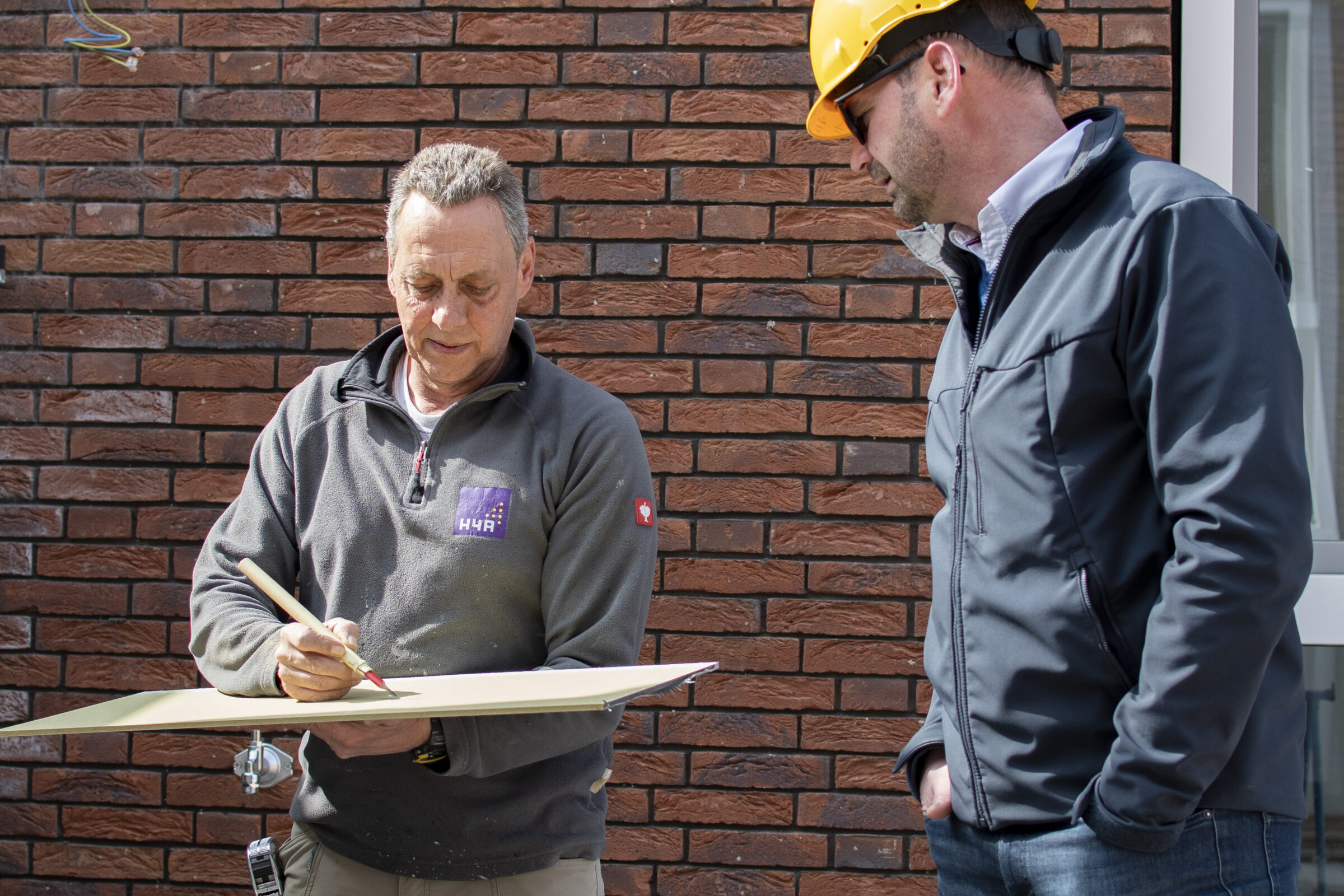 Twee medewerkers H4A Bouw geven uitleg