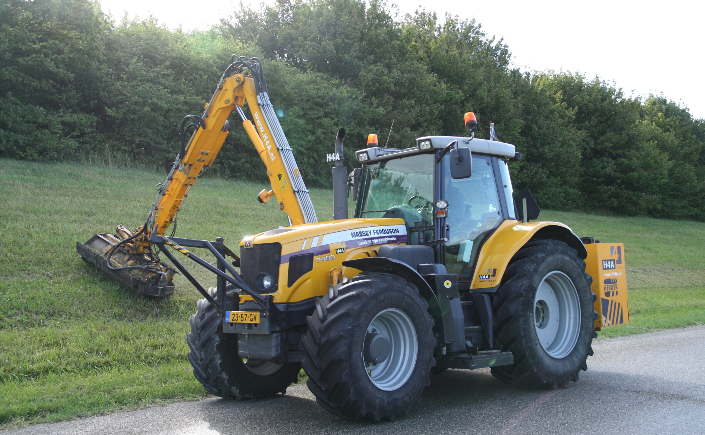 Tractor en arm met mulchdek van H4A groen maait het gras