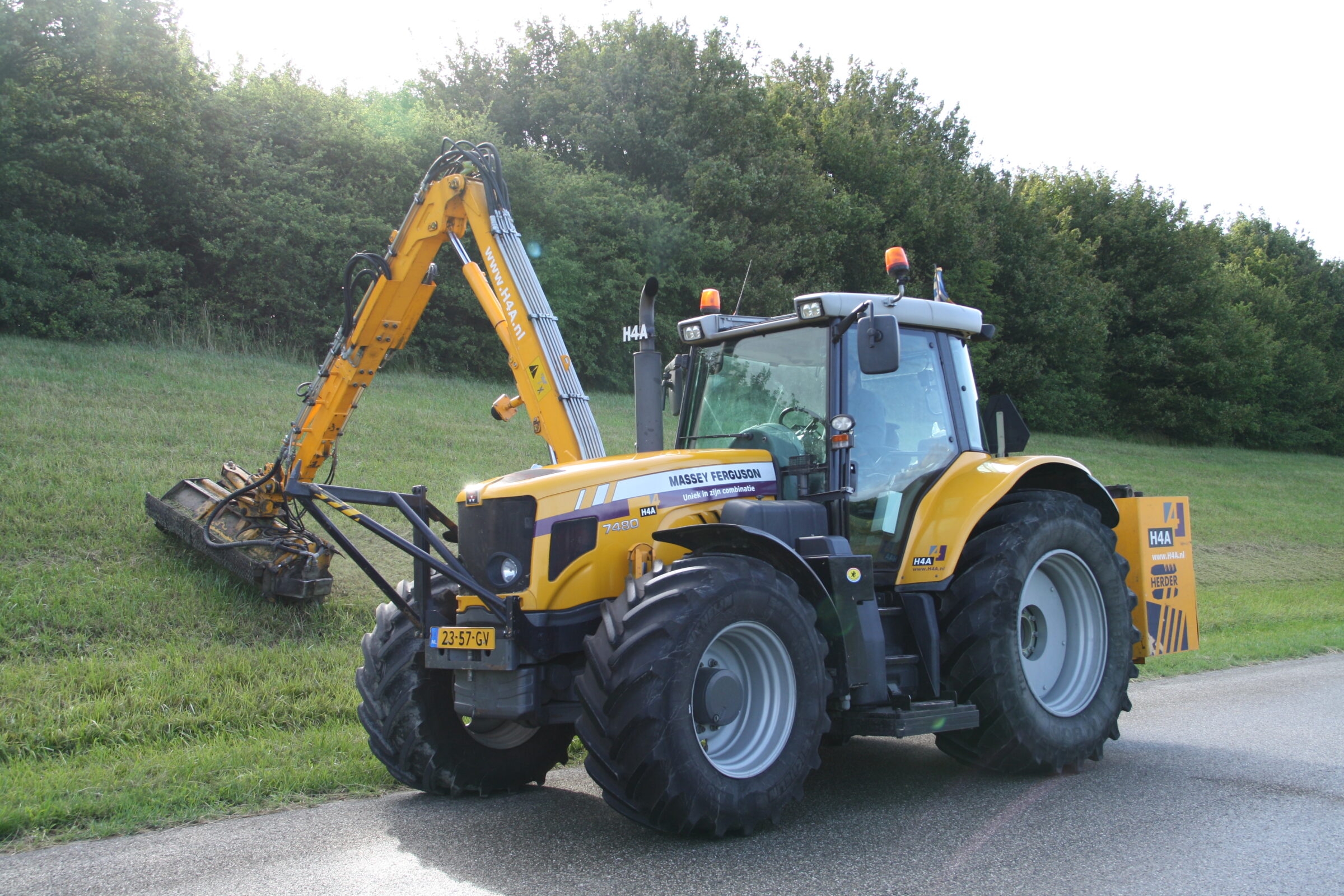Tractor en arm met mulchdek van H4A groen maait het gras