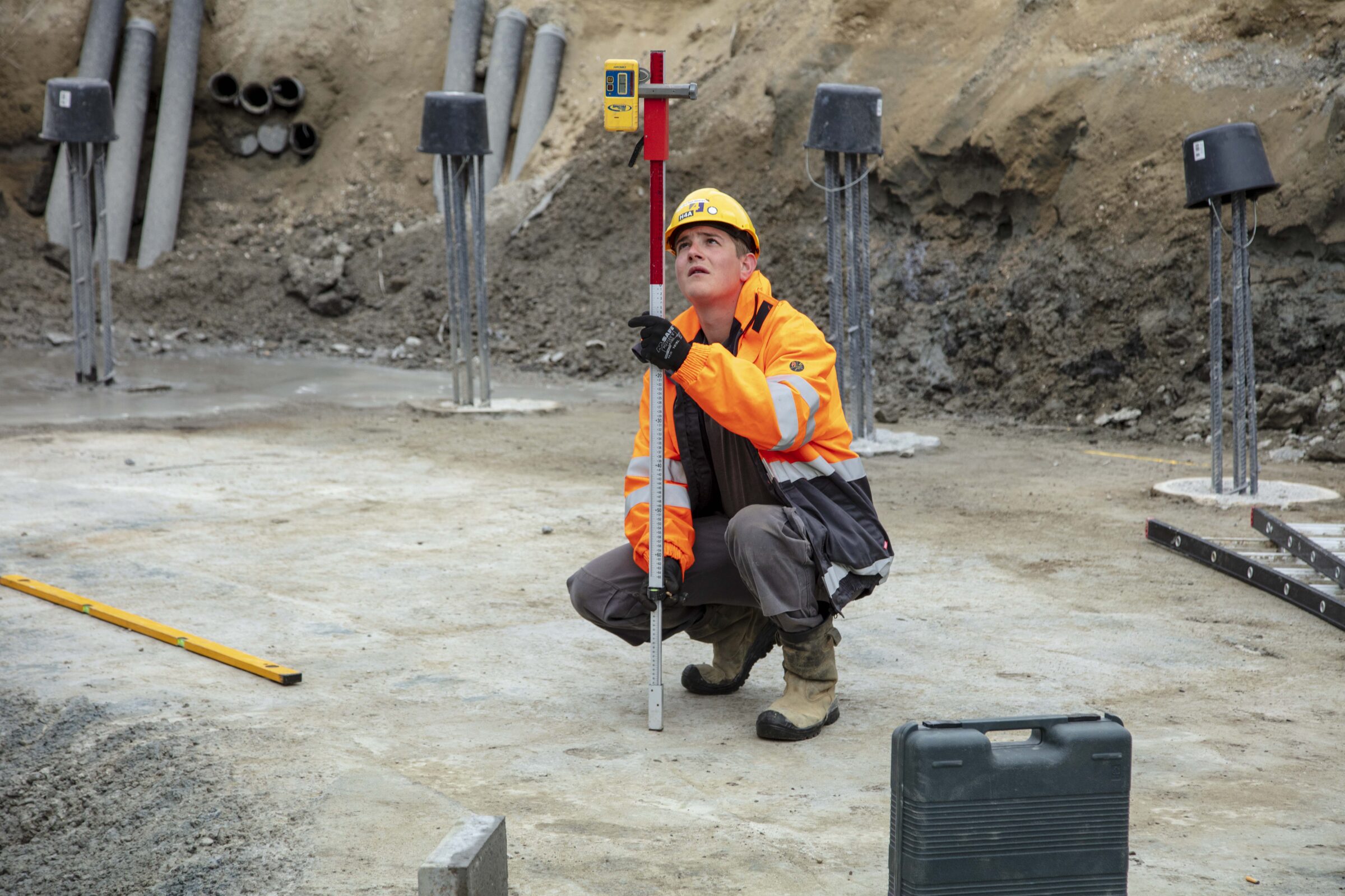 Medewerker H4A Windenergie meet de hoogte bij de fundering voor een windmolen