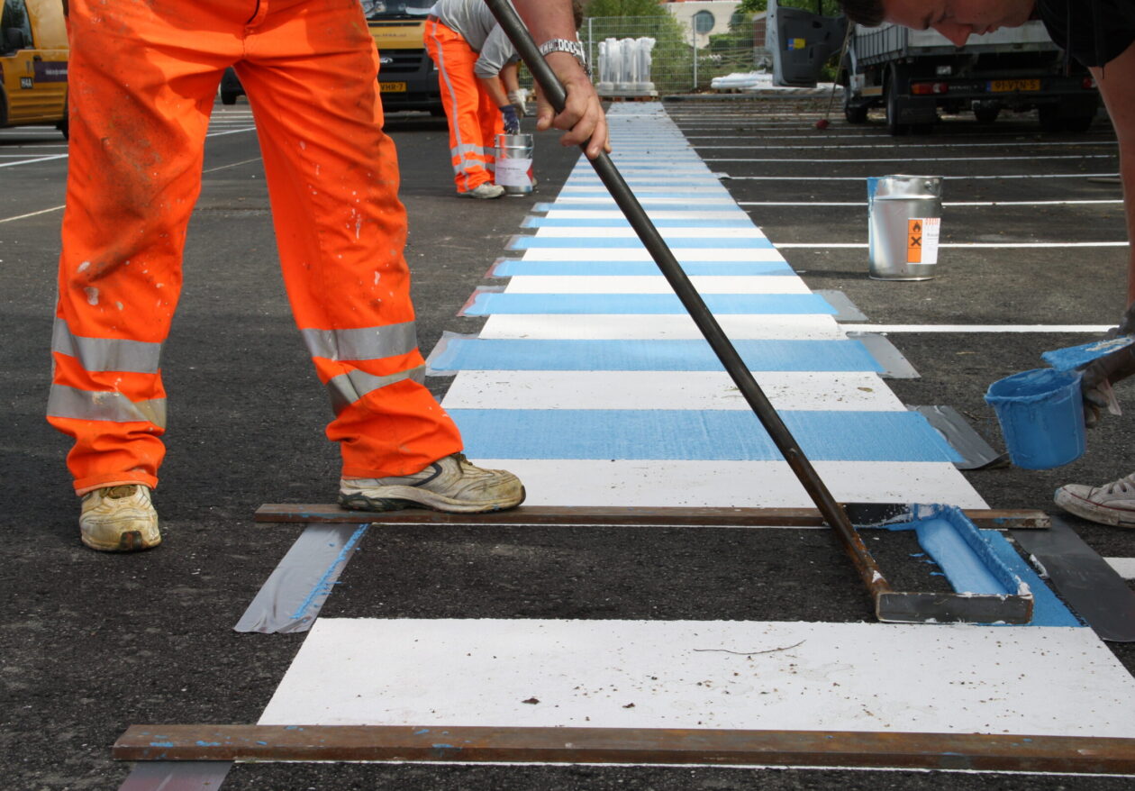 Medewerkers H4A Openbare Ruimte wegmarkeringen maken een zebrapad op parking