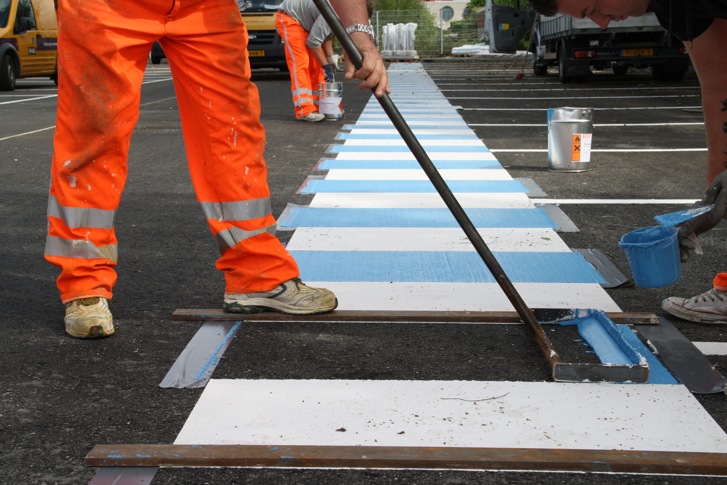 Medewerkers H4A Openbare Ruimte wegmarkeringen maken een zebrapad op parking